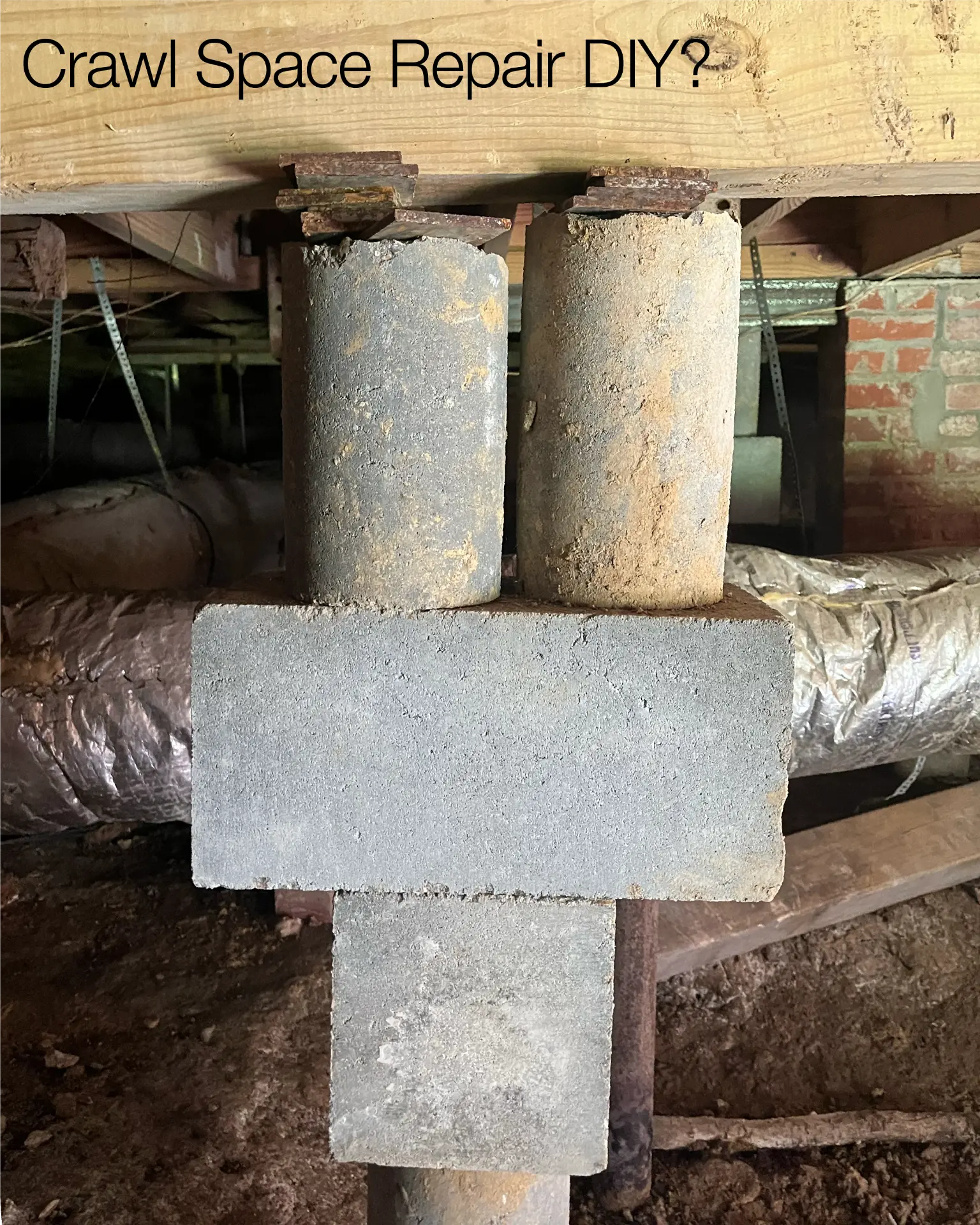 Concrete blocks and a rusted post stacked as a makeshift crawl space repair